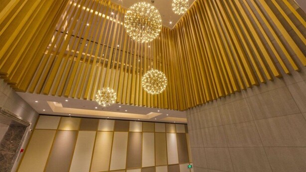 A modern interior with vertical wooden slats, geometric wall panels, and spherical decorative lights. - Linzhen Hotel (Shanghai)