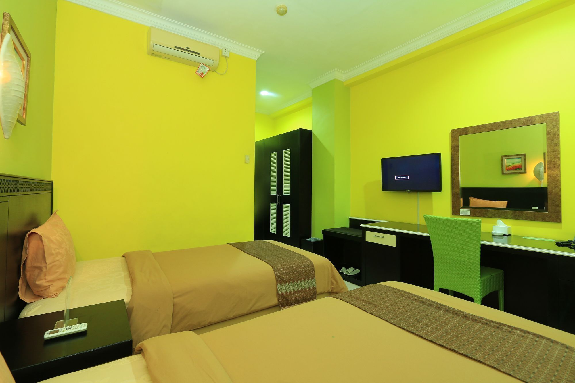 A hotel room with two beds, a desk, a chair, a TV, and a wardrobe.