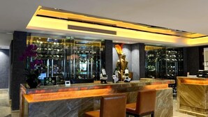 A reception area with a marble counter, two brown leather chairs, a glass display case with wine bottles, and a decorative golden sculpture. - Zhongshan Panshan Hotel (Zhongshan)