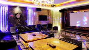 A modern lounge with a large sofa, a wooden coffee table, and a projector screen. - Zhongshan Panshan Hotel (Zhongshan)