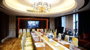 A conference room with a long table, chairs, a chandelier, and a television screen. - Zhongshan Panshan Hotel (Zhongshan)