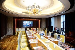 A conference room with a long table, chairs, a chandelier, and a television screen. - Zhongshan Panshan Hotel (Zhongshan)