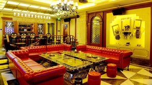 A lobby with a red leather sofa, a glass coffee table, and a chandelier. - Zhongshan Panshan Hotel (Zhongshan)