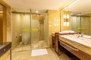 Un baño moderno con ducha de vidrio, lavamanos de mármol y un espejo grande.