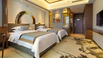 Habitación de hotel con dos camas, una obra de arte grande en la pared y un televisor montado.