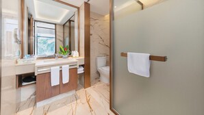 A modern bathroom with a glass-enclosed shower, a marble-tiled floor, and a large mirror above the sink. - Donghu Grand Hotel (Jieyang)
