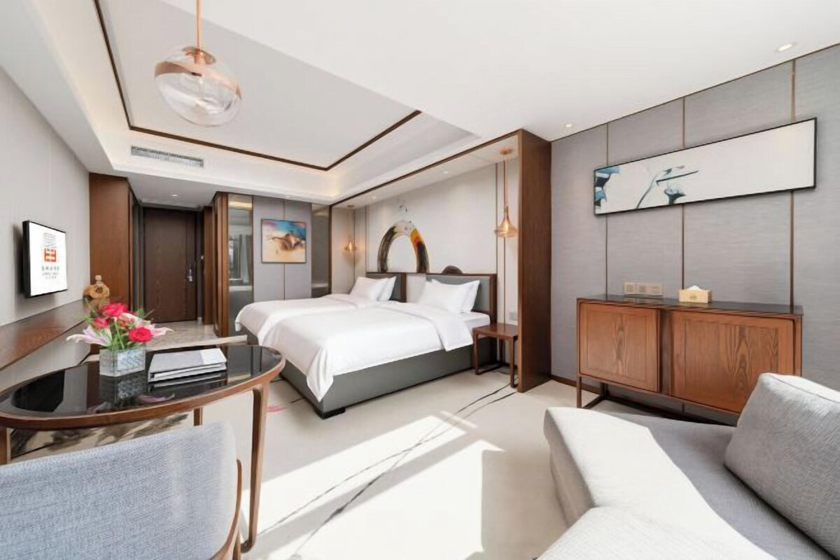 Quarto de hotel moderno com cama, escrivaninha, sofá e armário.