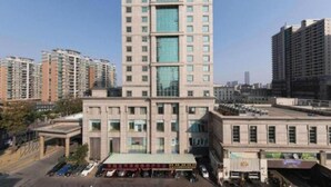 Un edificio de varios pisos con una entrada destacada y un porche con techo rojo.