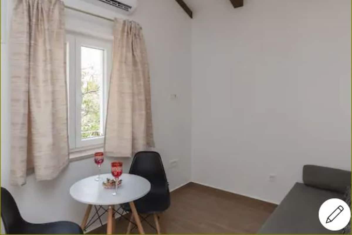Una habitación con ventana, dos sillas, una mesita redonda y un sofá.
