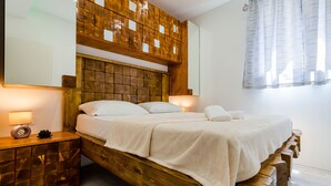 Een houten bed met hoofdeinde, nachtkastjes en een raam met gordijnen.