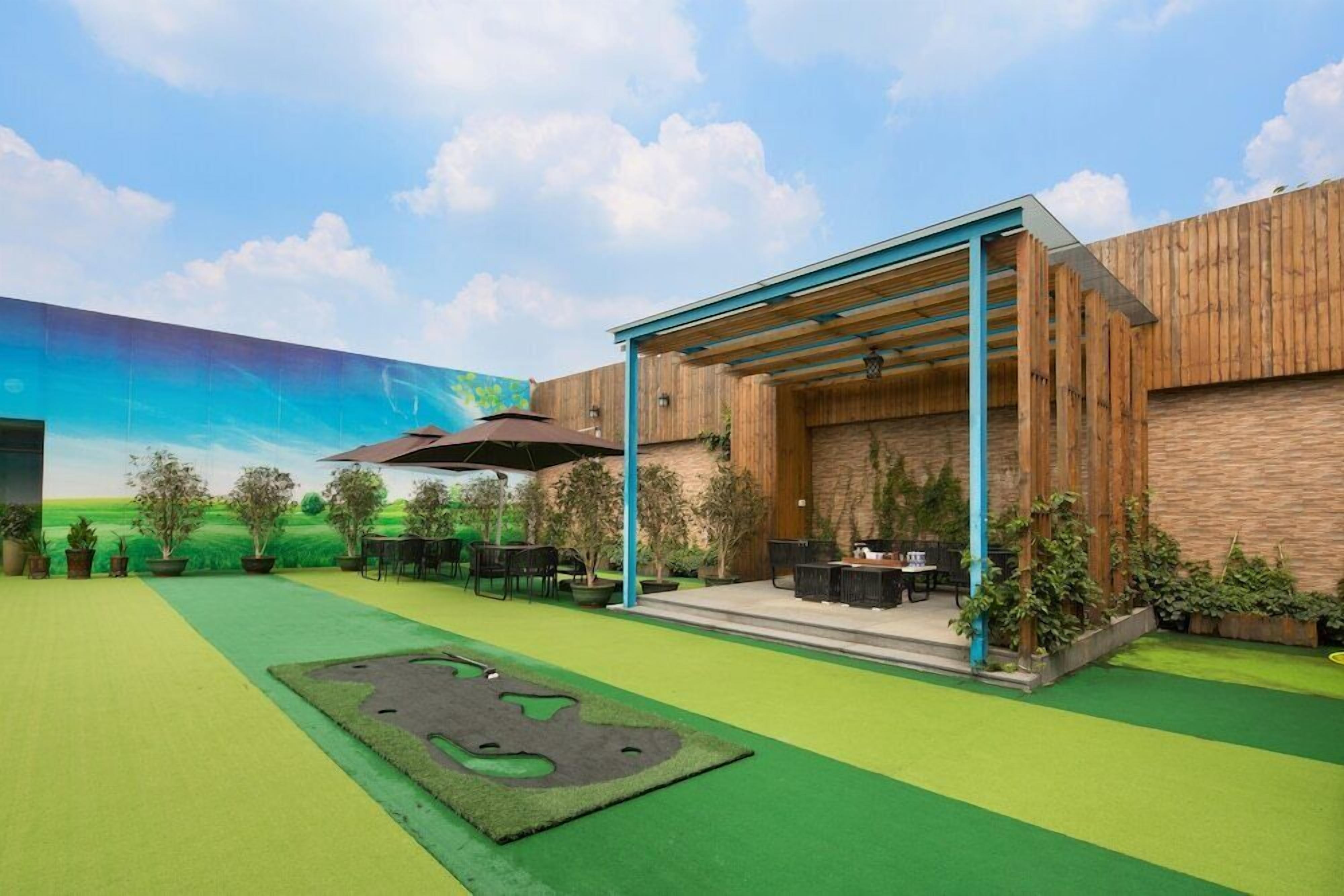 A modern outdoor patio area with a wooden pergola, seating, and a mural on the wall.