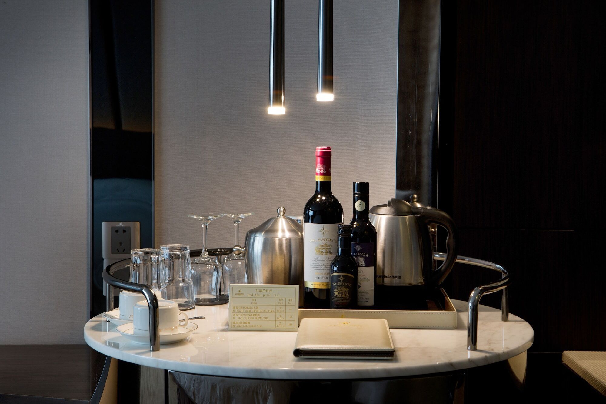 A round table with a wine bottle, glasses, a teapot, and a menu.