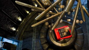Una escalera de caracol con un objeto rojo y negro en el centro, rodeado de barras metálicas y elementos esféricos.