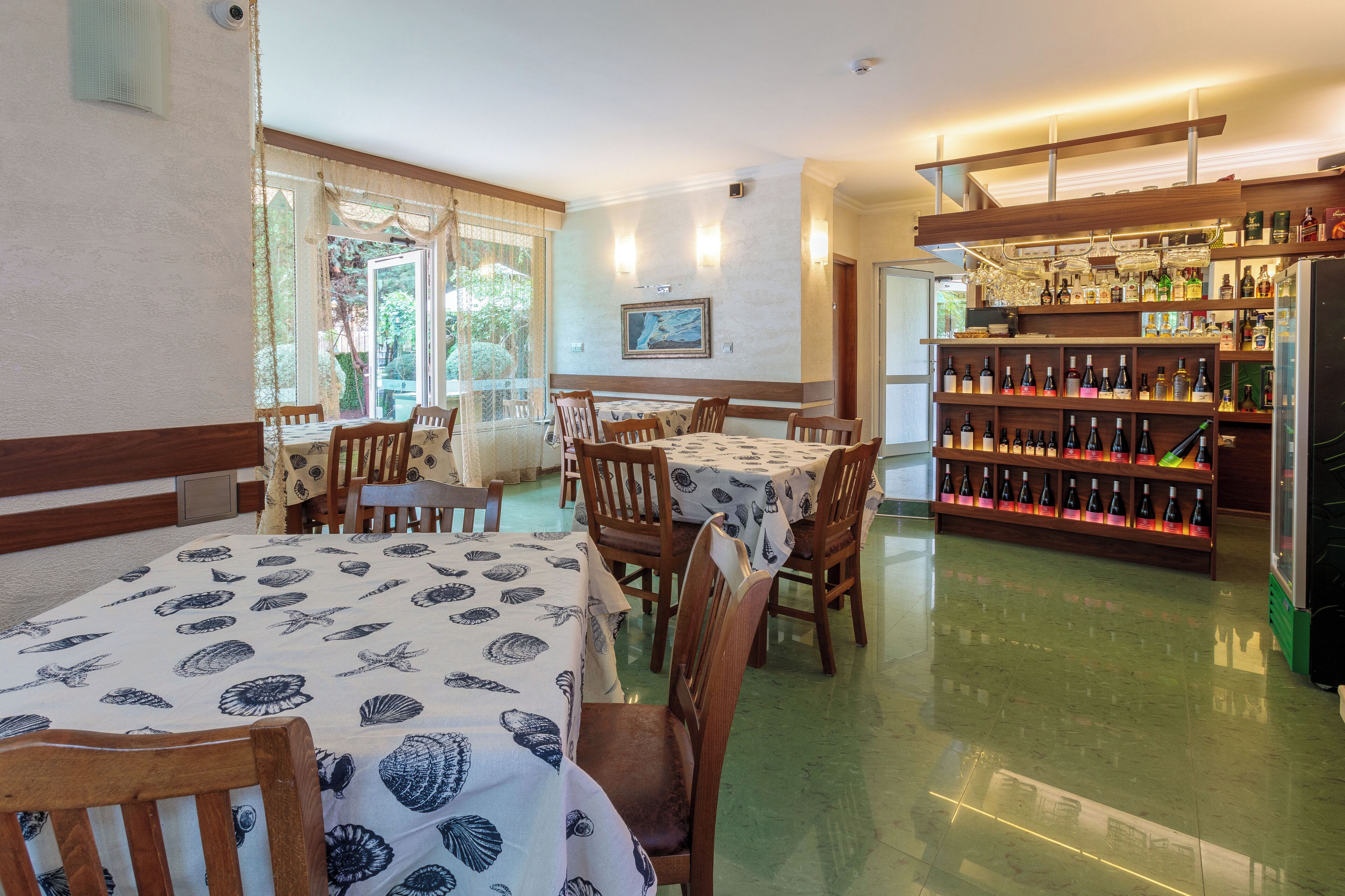 A restaurant with wooden tables and chairs, a wine rack, and a large window.