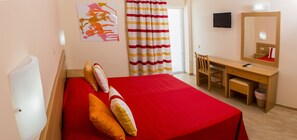 A hotel room with a bed, a desk, a chair, a television, and a mirror. - Hotel Delphi Beach - All Inclusive (Dorida)
