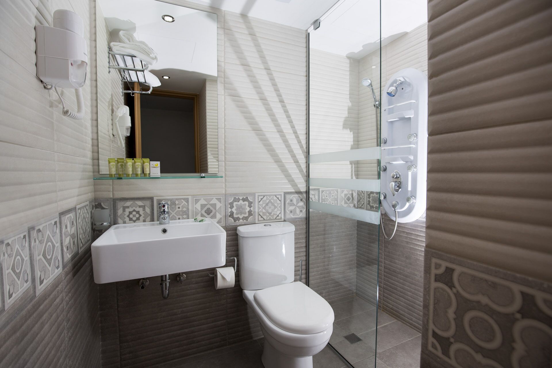 Une salle de bain moderne avec un lavabo blanc, des toilettes et une douche à parois de verre.