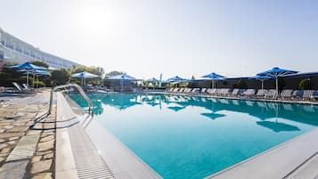 Una piscina al aire libre, sombrillas, sillones reclinables de piscina