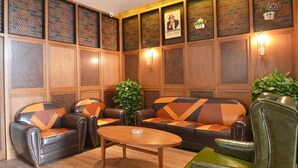 A room with a wooden paneled wall, a sofa set, a coffee table, and wall-mounted lights. - James Joyce Coffetel (Zhengzhou)