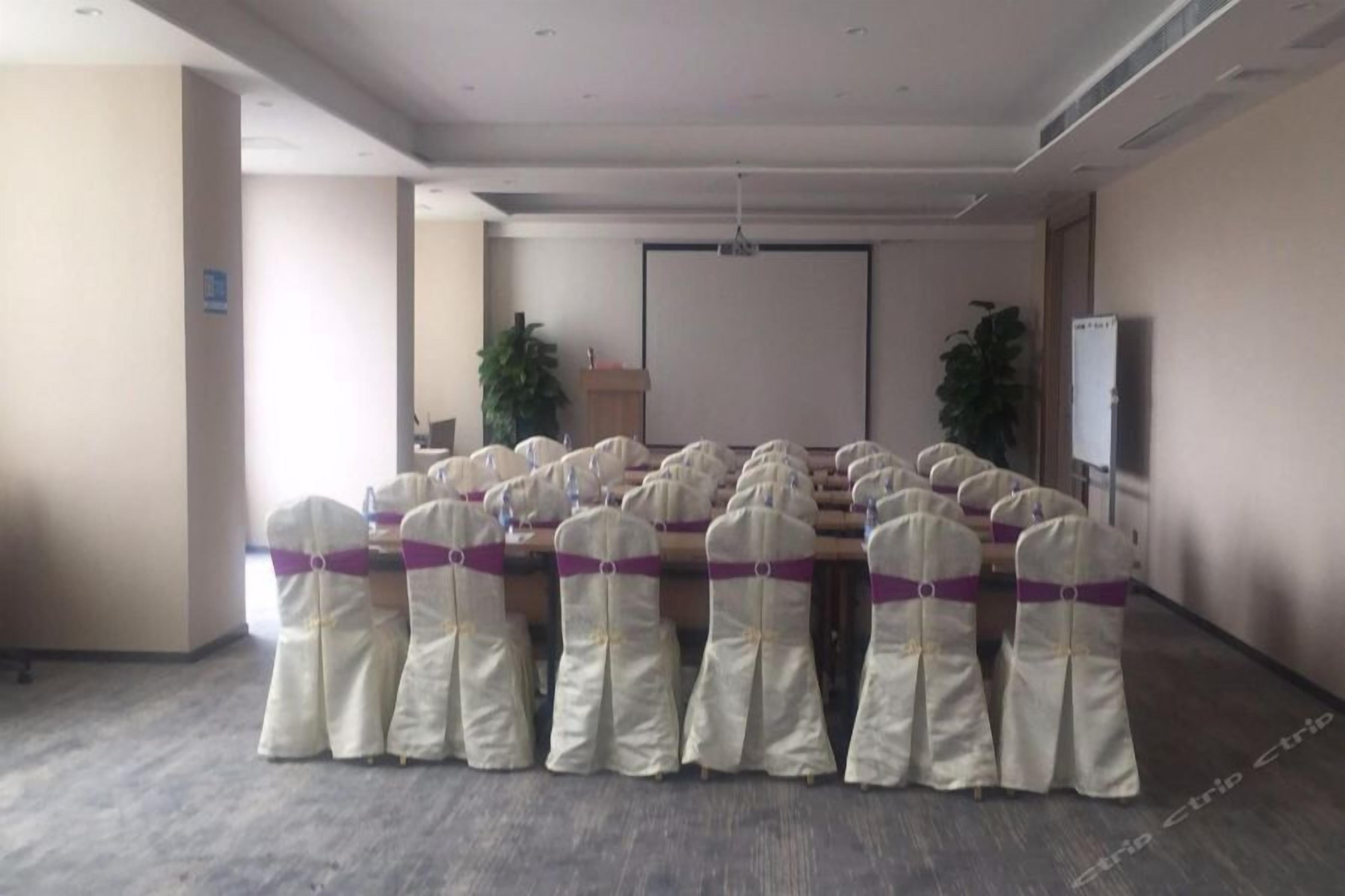 A conference room with rows of chairs, a projector screen, and a podium.