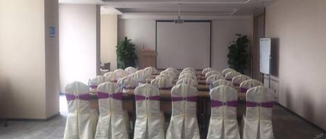 A conference room with rows of chairs, a projector screen, and a podium.