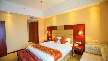 A hotel room with a large bed, bedside tables, a chair, and a red hanging decoration.