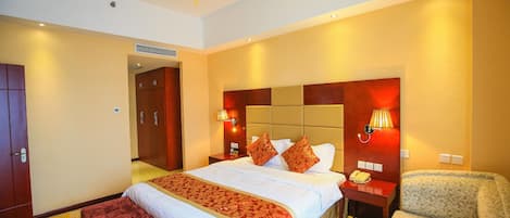 Habitación de hotel con una cama grande, mesitas de noche, una silla y un adorno colgante rojo.