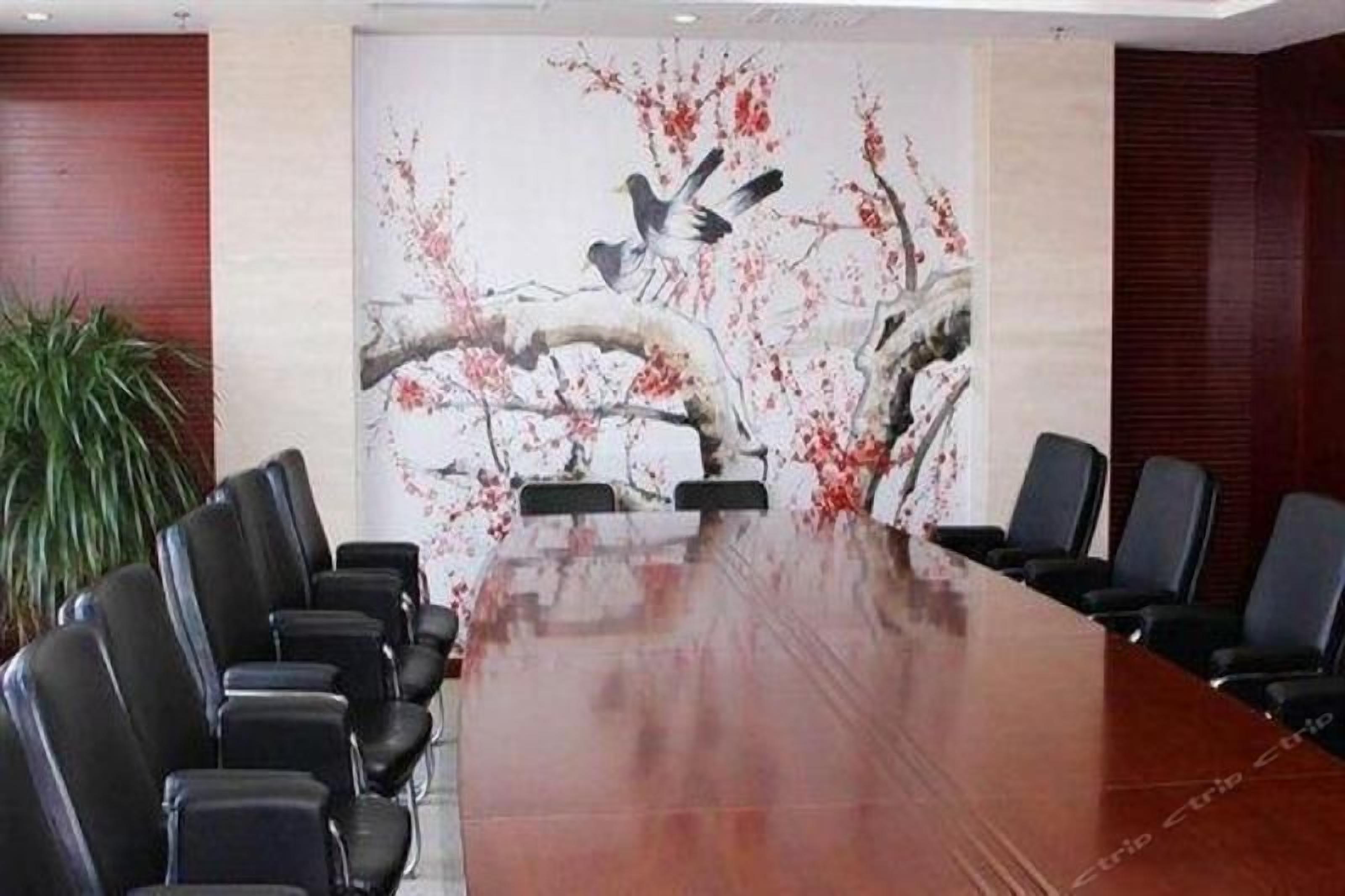 A conference room with a long table and multiple chairs, a large painting on the wall, and a potted plant.