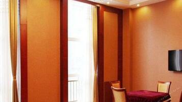 Habitación de hotel con un ventanal grande, un televisor de pantalla plana montado en la pared y una mesa de comedor con sillas.