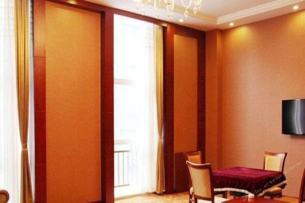 A hotel room with a large window, a flat-screen TV mounted on the wall, and a dining table with chairs. - Tianxinliang Hotel (Beijing)