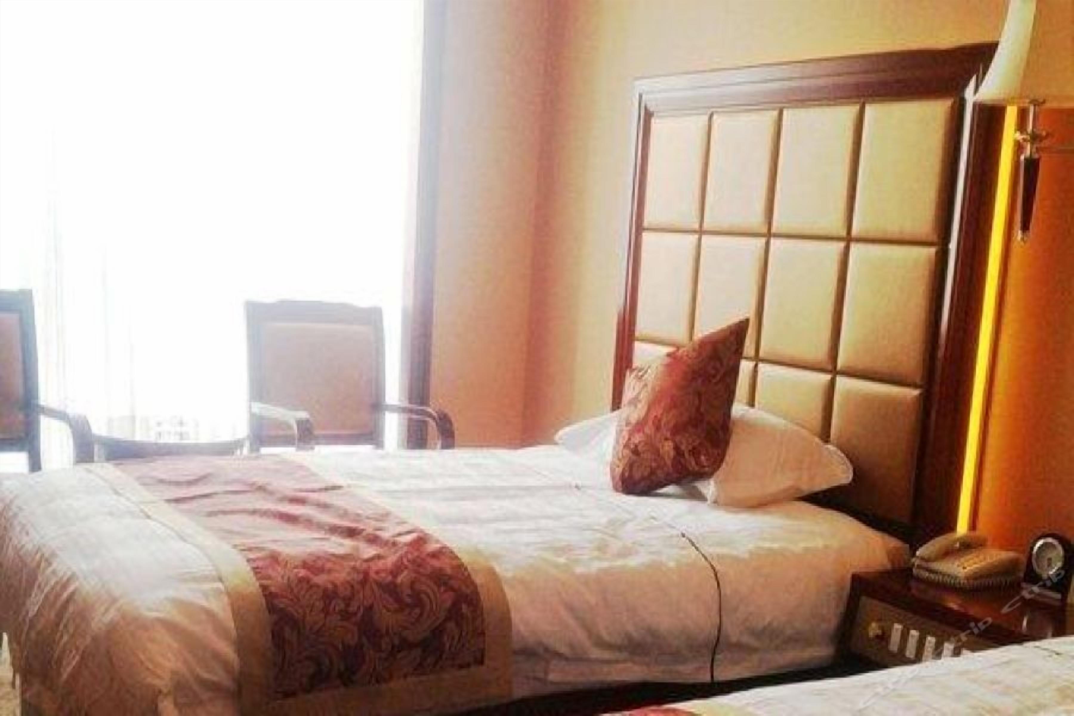 Une chambre d’hôtel avec un grand lit, une table de chevet avec une lampe et une fenêtre avec des rideaux.