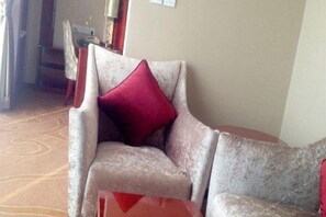A corner seating area with a cushioned chair and a red pillow. - Tianxinliang Hotel (Beijing)