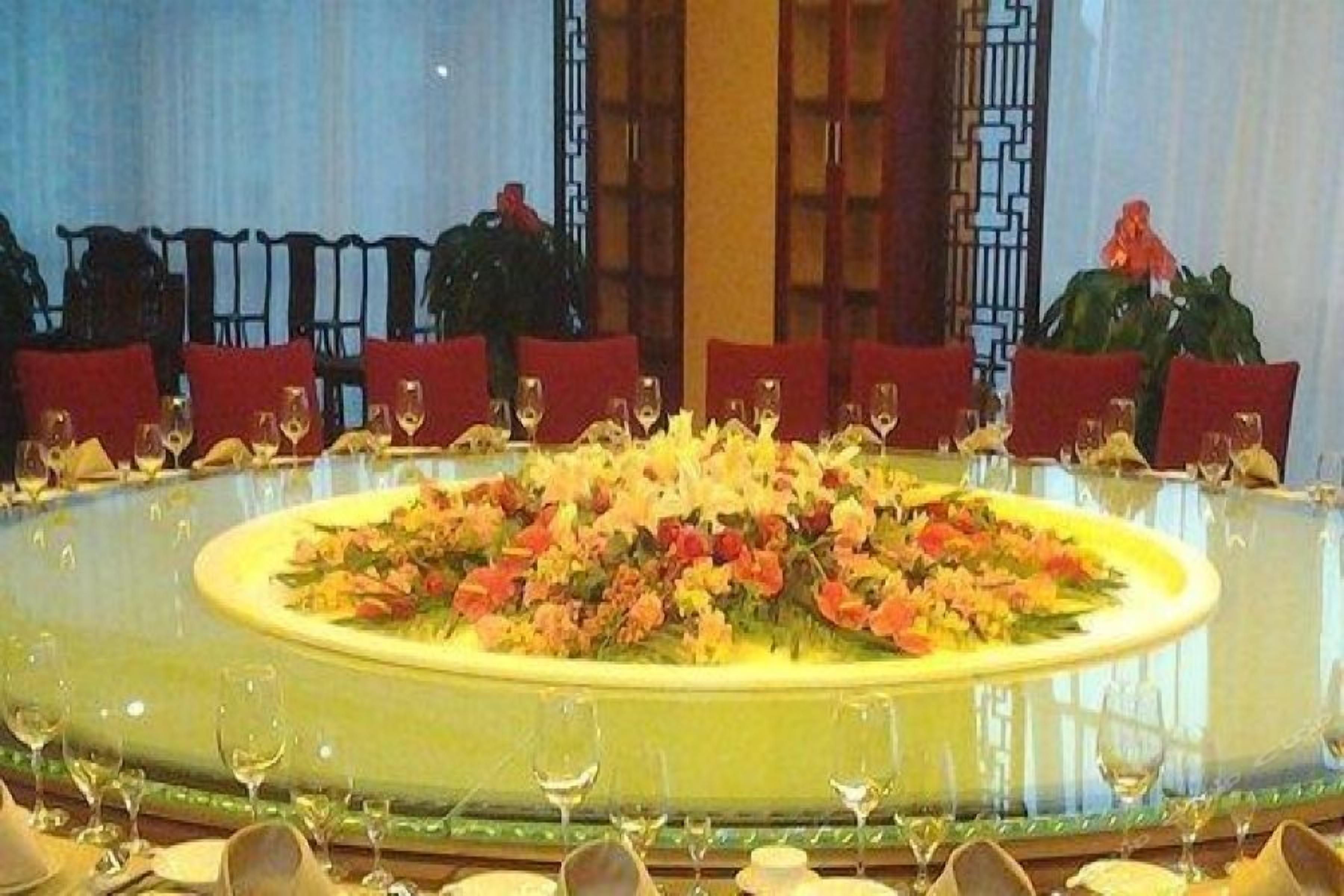 Mesa de jantar redonda com cadeiras, arranjo floral central e copos de vinho.