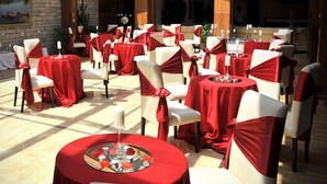 A formal outdoor dining area with round tables and chairs, each set with red tablecloths and white chairs. - Rozafa Hotel (Shkodër)