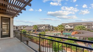 A balcony with a view of a residential area, including houses, a swimming pool, and palm trees. - Ocotillo Springs #20 Beautiful Unit Close to Trails/Hiking (Santa Clara)