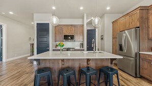 A modern kitchen with a large island, wooden cabinets, stainless steel appliances, and bar stools. - Ocotillo Springs #20 Beautiful Unit Close to Trails/Hiking (Santa Clara)
