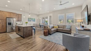 A modern kitchen with wooden cabinets, stainless steel appliances, and a dining area with a chandelier. - Ocotillo Springs #20 Beautiful Unit Close to Trails/Hiking (Santa Clara)