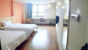 A hotel room with two beds, a desk, a chair, a TV, and a large window.