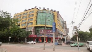 A multi-story building with a yellow facade and a green glass section.