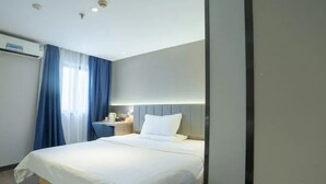 Une chambre d’hôtel avec un grand lit, une table de chevet avec une lampe et une fenêtre avec des rideaux bleus.