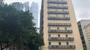 Un immeuble à plusieurs étages, doté de balcons, entouré d’arbres et d’autres bâtiments.