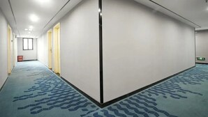 Un long couloir étroit, doté d’un tapis à motifs, de murs blancs et d’un mur d’accent noir.