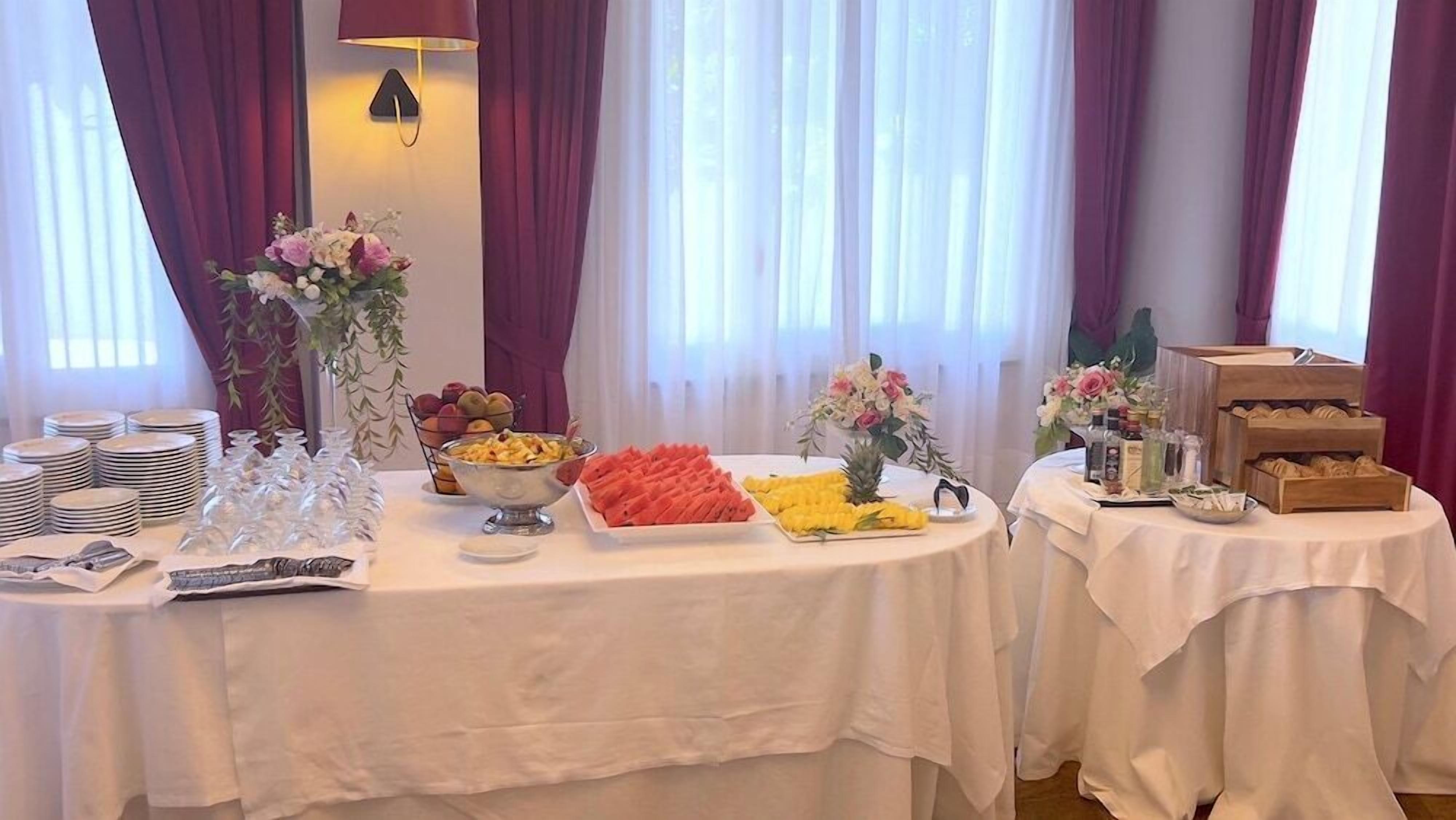 A buffet setup with various food items, glassware, and floral centerpieces.