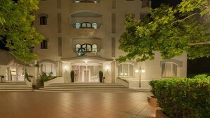 Una entrada de hotel con una imponente escalera, fachada bien iluminada y diseño simétrico.