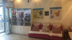 A reception area with a red sofa, glass display cabinets, and informational posters on the wall.