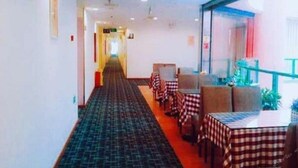 A hotel corridor with checkered tablecloths, a carpeted floor, and a glass railing overlooking a balcony. - 7 Days Inn (Xiamen)