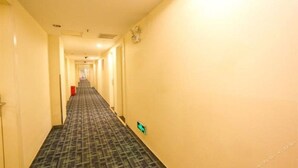A hotel hallway with carpeted floors and a light-colored wall. - 7 Days Inn Jinhuabei Road (Xi'an)