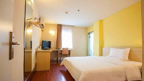 Una camera d'albergo con un letto, una scrivania, una sedia, una televisione e uno specchio.