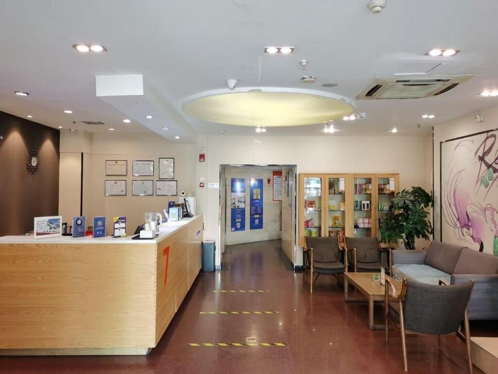 A reception area with a wooden desk, framed certificates, a coffee machine, and a seating area with chairs and a sofa.