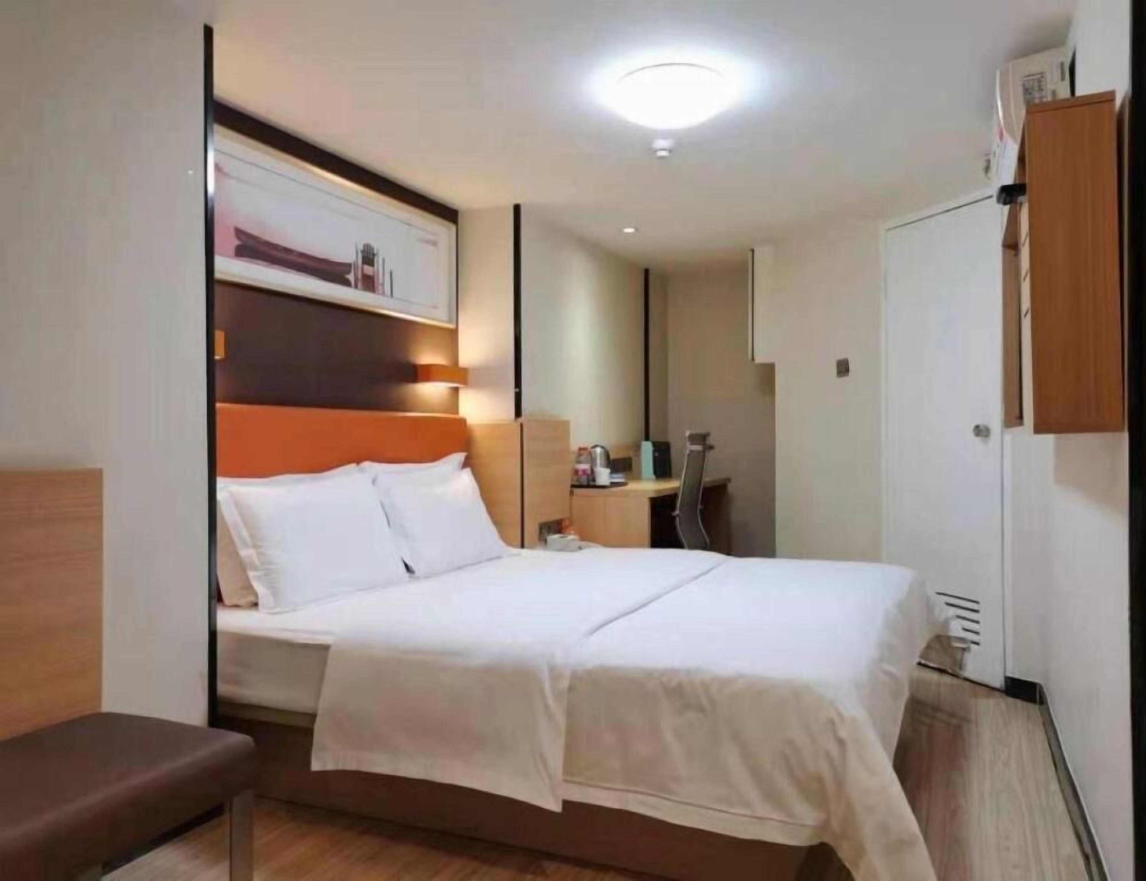 Una habitación de hotel con cama, escritorio, silla y armario.
