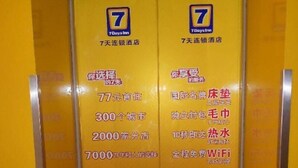 A yellow elevator interior with two signs indicating a 7-day stay. - 7 Days Inn Harbin Railway Station Qiulin Shop (Harbin)